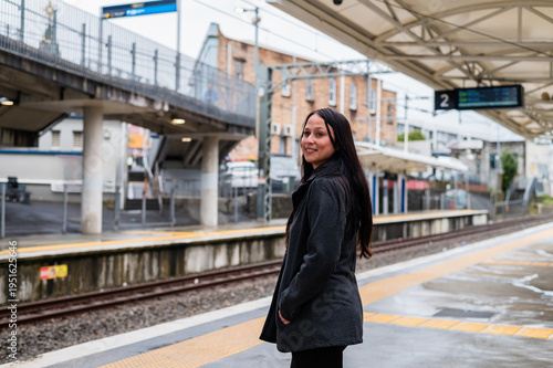 Woman wearing black coat waiting on the platform at train station