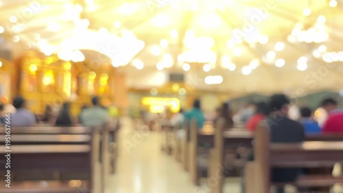 Interior view of catholic church with congregation during religious mass service, blurred bokeh of people in pews