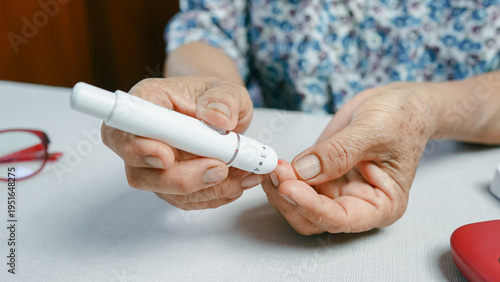 Close up of senior woman using lancet device for finger prick blood test, showing diabetes monitoring and glucose control. Elderly healthcare and chronic disease management concept.