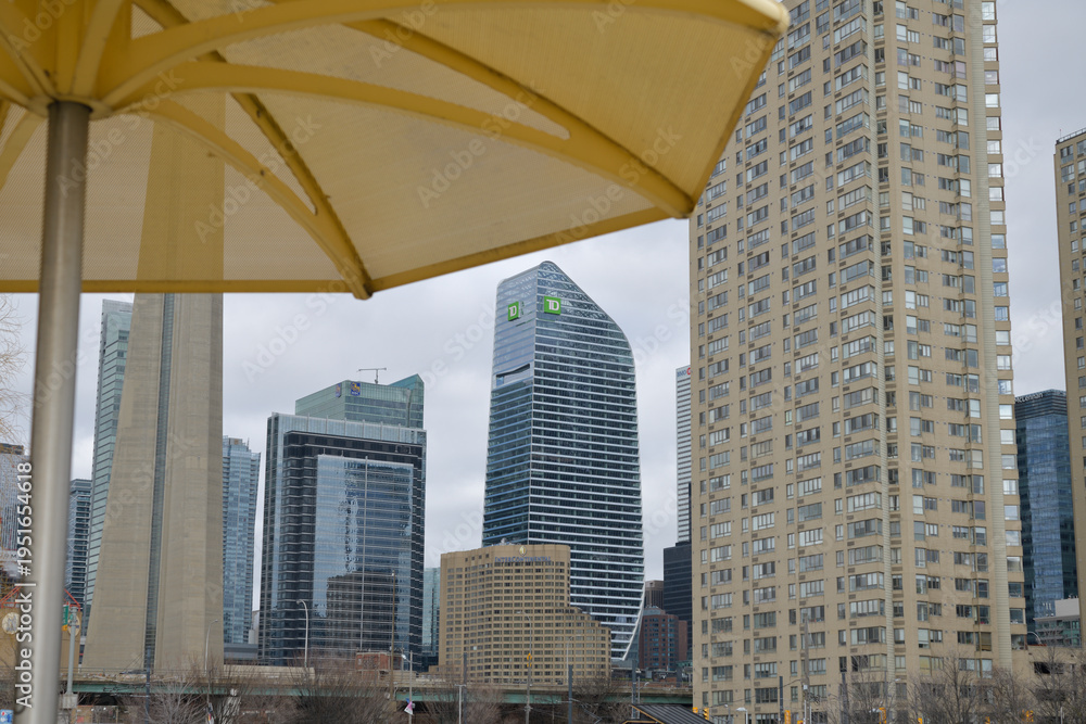 Fototapeta premium defocused metal beach umbrella at HTO Park and view of TD Terrace, office buildings, and Continental hotel, Toronto