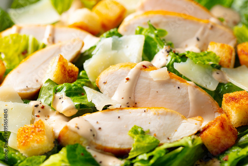 Fresh chicken Caesar salad with crisp croutons, creamy dressing, parmesan shavings, vibrant lettuce. Close up.