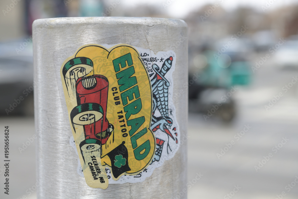 Fototapeta premium close-up of street slaps for Emerald Club Tattoo located in Selkirk, Manitoba (Gordie Farrell) over another sticker in Toronto