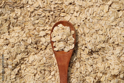 Close-up texture of rolled oats. Perfect for backgrounds, healthy eating, and natural food concepts. Oats on a wooden spoon .