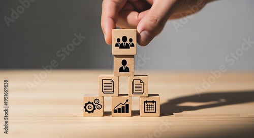 Hand stacking wooden blocks with business icons representing organizational structure human resources management and corporate team building strategy