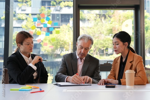 A group of business executives signed documents while their secretaries and staff sat beside them, reviewing the contracts in the company's conference room