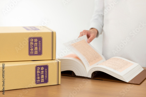 Obraz na płótnie 会社規程の手引書をめくる人事担当者 就業規則の策定とコンプライアンスのイメージ