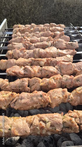 The kebabs are grilled on the coals while rotating.