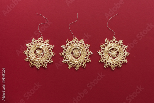 Snowflakes are made of straw on a red background. Straw star. Christmas decor. Top view. Straw weaving