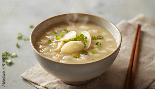 A warm and inviting bowl of traditional Asian congee, made with tender rice porridge, topped with thin slices of fresh ginger and sprinkled with chopped green scallions.