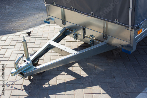 Canvas Print Galvanized steel utility trailer with a grey tarp cover parked on pavement