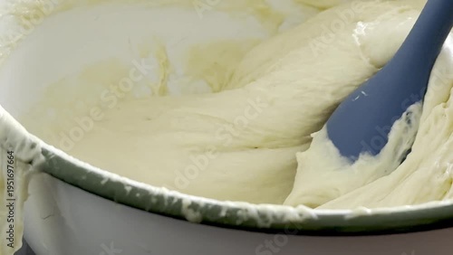 Mixing batter in a white bowl with a thick, creamy texture, showing the gradual incorporation of ingredients and the smooth consistency achieved in the process