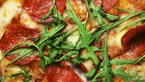Pepperoni pizza texture with fresh arugula, top view Italian cuisine background