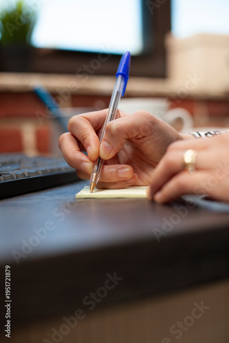 Tableau sur toile Hands of a female employee jotting down strategy ideas on adhesive notes at her desk