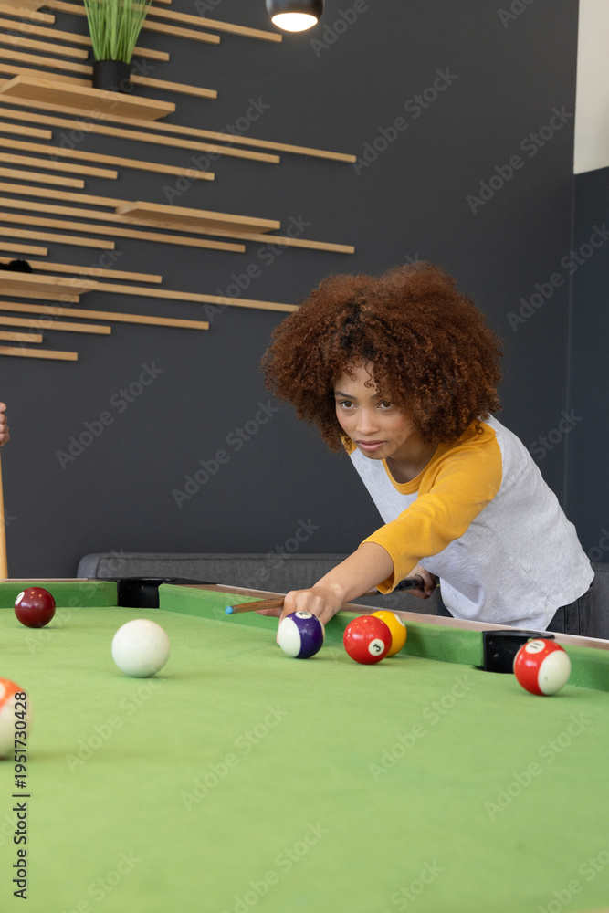 Naklejka premium Teen friends playing on green pool table in game room, wearing raglan, aiming cue, copy space