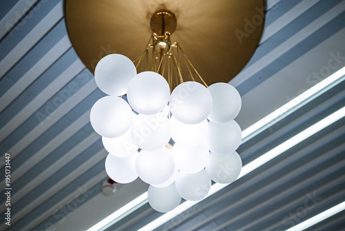 Stylish Light Fixture. Rustic Brass Canopy Supports Frosted Glass Globes. Elegant Lighting Setting Featuring Chandelier With Brass And Frosted Glass Globes Makes Cozy Ambiance