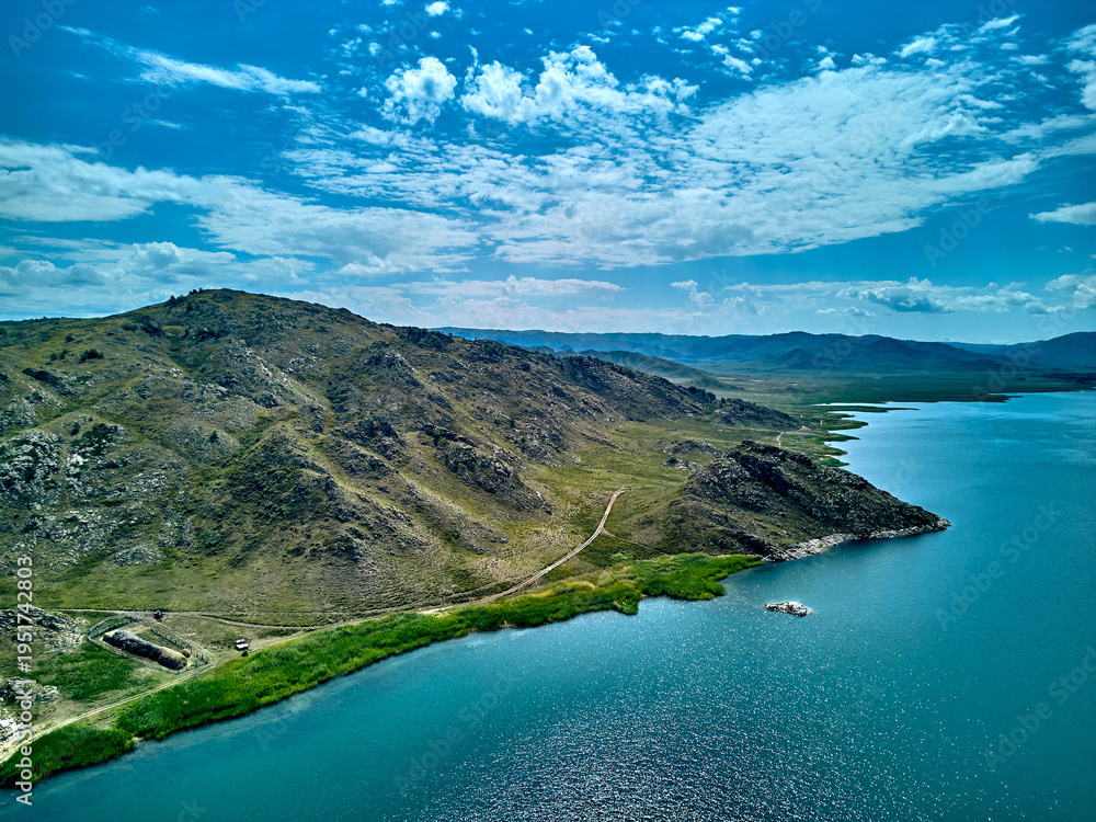 Obraz premium Aerial view of a remote sandy beach and rugged coastline with mountains and island under a moody sky, on the Bukhtarma Reservoir, on the Irtysh River, in Kazakhstan (Qazaqstan)
