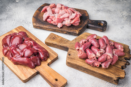Obraz na plátne Assorted raw giblets including hearts, liver, and gizzards on vintage wooden boards, organic poultry cooking concept