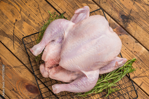 Foto Whole fresh raw chicken on a cooling rack with rosemary and thyme