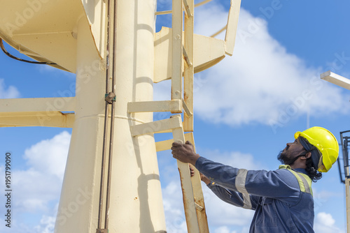 Bild auf Leinwand Seafarer in protective gear climbing vertical ladder on ship’s navigation mast during routine maintenance