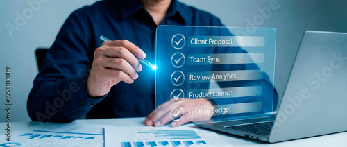 A professional is working diligently on the task list in front of the laptop, the checklist showing important work tasks