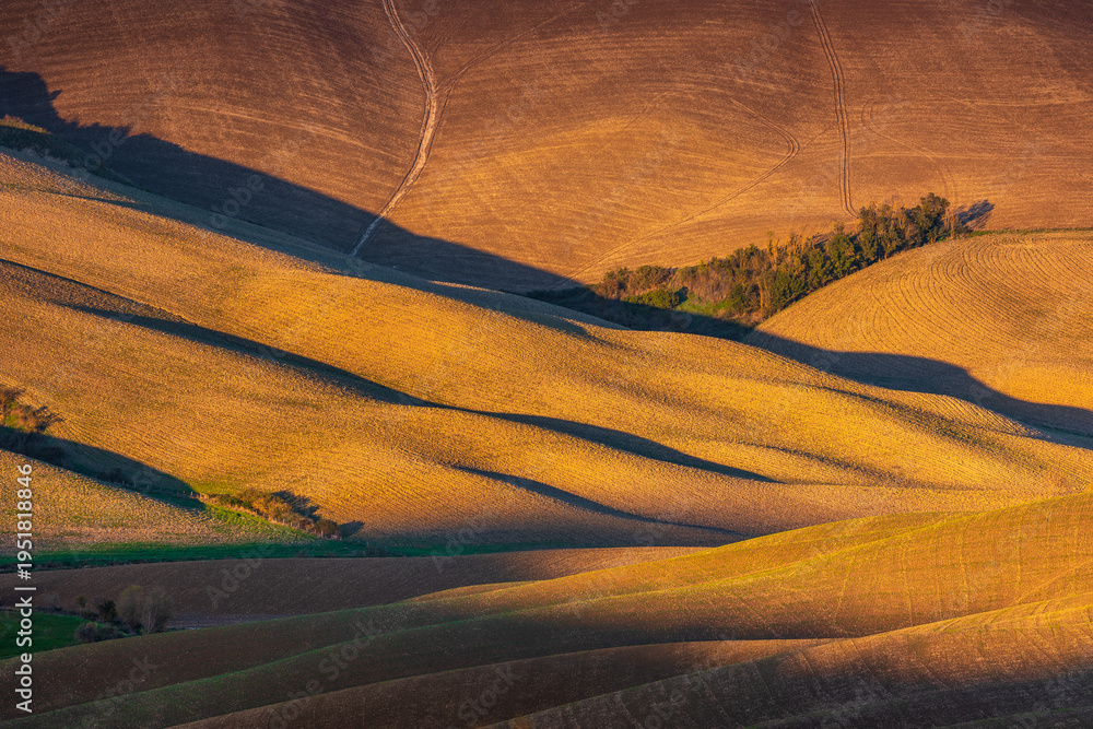 Obraz premium Rolling Tuscan hills creating abstract shadow patterns, Italy.