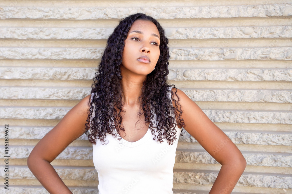 Fototapeta premium Fashionfocused woman against textured background. Young woman with curly hair in elegant dress