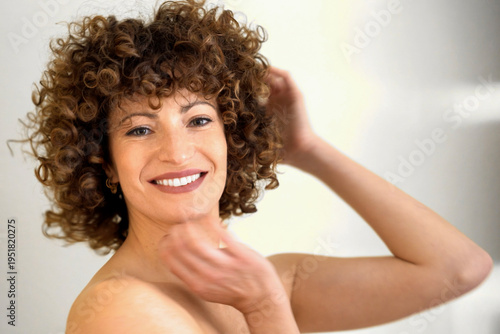 Sophisticated woman with flowing curls showcases serenity and natural allure in soft lighting