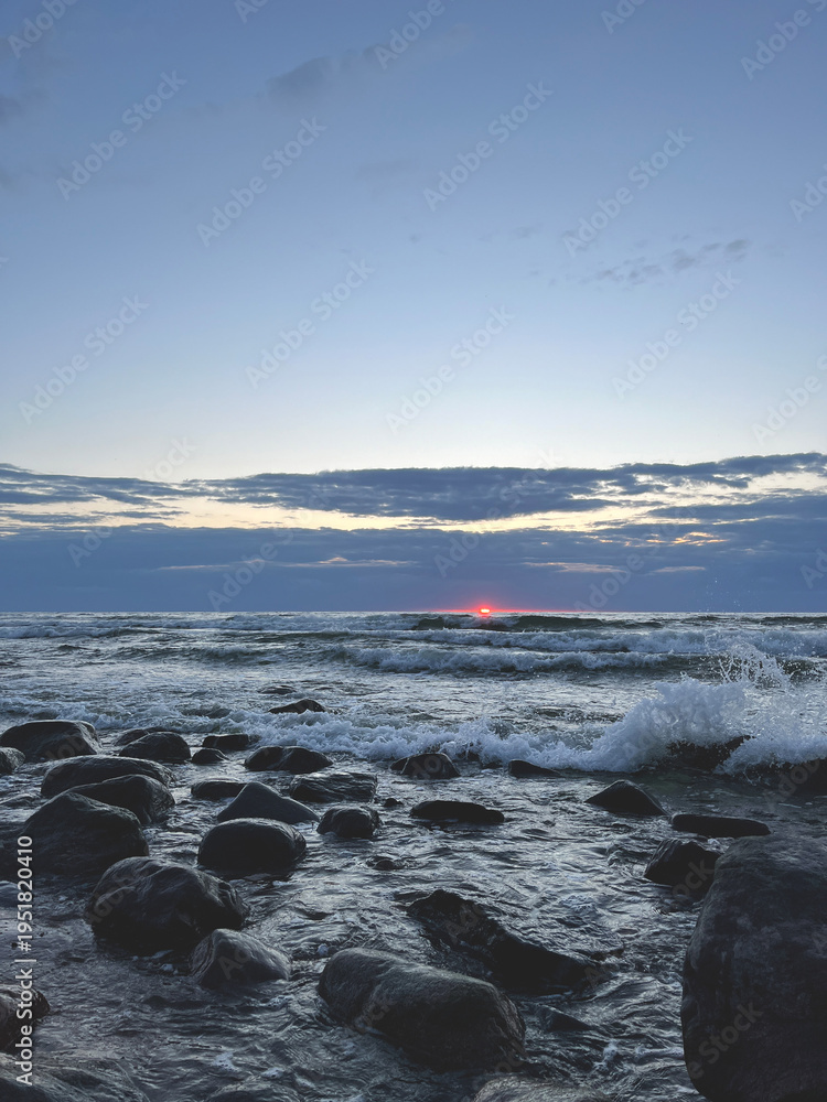 Fototapeta premium A beautiful sunset at sea. Waves crashing against the rocks.