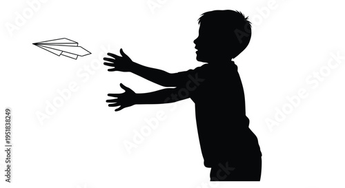 Silhouette of a young boy reaching for a paper airplane in flight