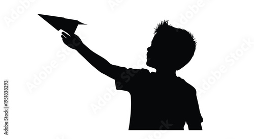 Silhouette of a young boy launching a paper airplane into the air