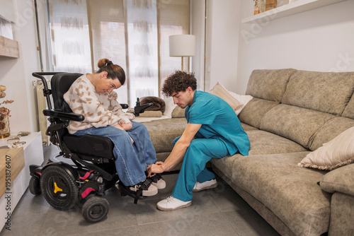 Fotografie Caregiver assisting woman in electric wheelchair at home