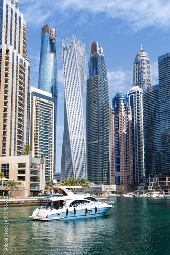 Tableau sur toile Luxury Yacht Cruising in Dubai Marina with Cayan Tower Backdrop