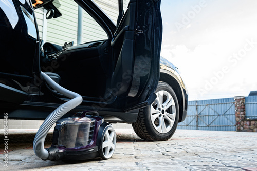 Cleaning and vacuuming the car with a vacuum cleaner outside in the spring.