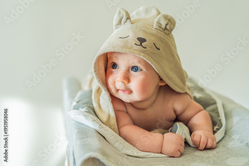 Baby lying on a changing table wrapped in a soft towel after bathing at home. Clean, calm and cozy moment of infant care and safety. Baby hygiene, daily routine and gentle parenting concept
