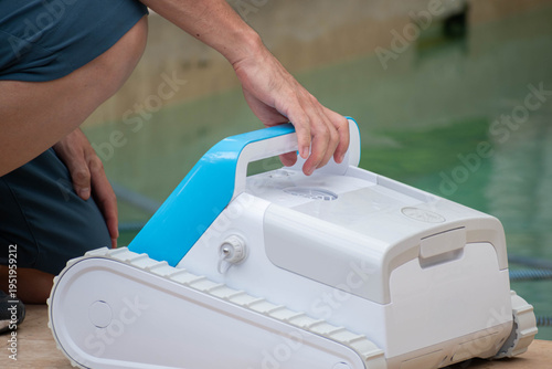 Automatic robotic pool cleaner being prepared for maintenance by poolside