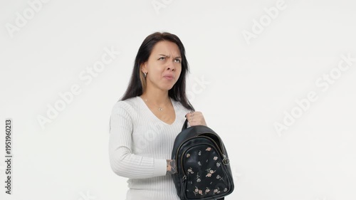 Nervous adult woman in casual clothing searching some lost thing in black purse, trying to find keys or some object