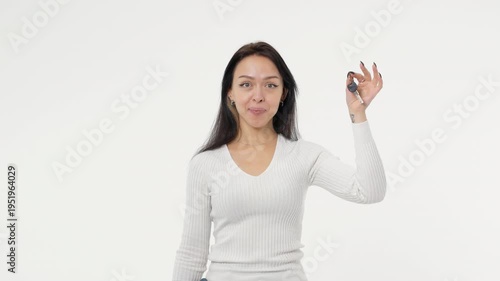 Young adult woman holds the keys to buying a car or apartment white background isolated space happy