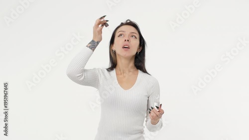 Young adult woman applies skin care serum to her face white background isolated space