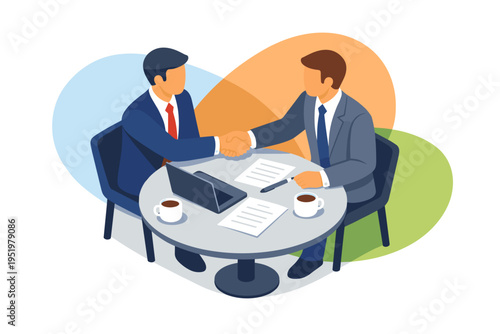 Two businessmen shaking hands over a round table with laptops and coffee.