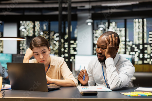 Tableau sur toile Multiracial team of employees in office feeling upset after missing project deadline, using laptop