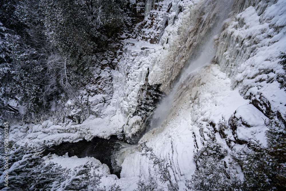 Fototapeta premium View of partially frozen waterfall and river in winter.