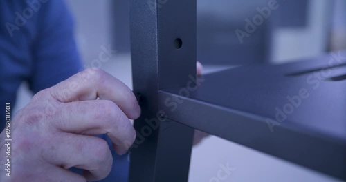 Grown man's hand twisting screw into hole in metal object