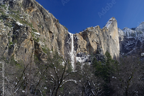 Fotografi Bridalveil Fall in Yosemite National Park, California, surrounded by snow‑dusted granite cliffs
