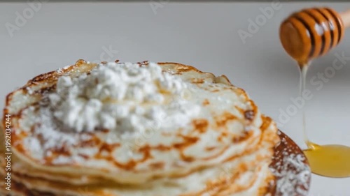 Stack of delicious crepes topped with fresh cheese and drizzled with honey