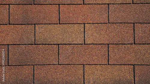 Fotografie A close-up of brown and tan asphalt roof shingles arranged in a staggered rectangular pattern