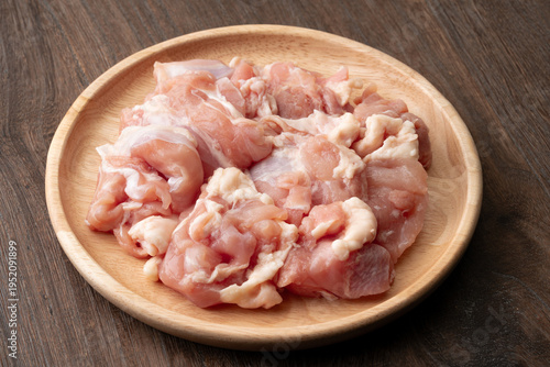 木製のお皿に載せた生の鶏もも肉のぶつ切り