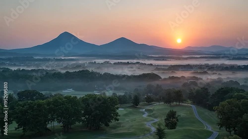 Sunrise over rolling hills and a misty valley with distant mountains
