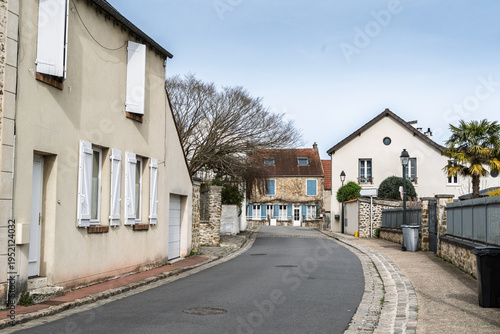Quiet residential street in Vieux Montigny, the historic core of Montigny le Bretonneux in Saint Quentin en Yvelines, France, showing traditional french village houses, shutters and stone walls.