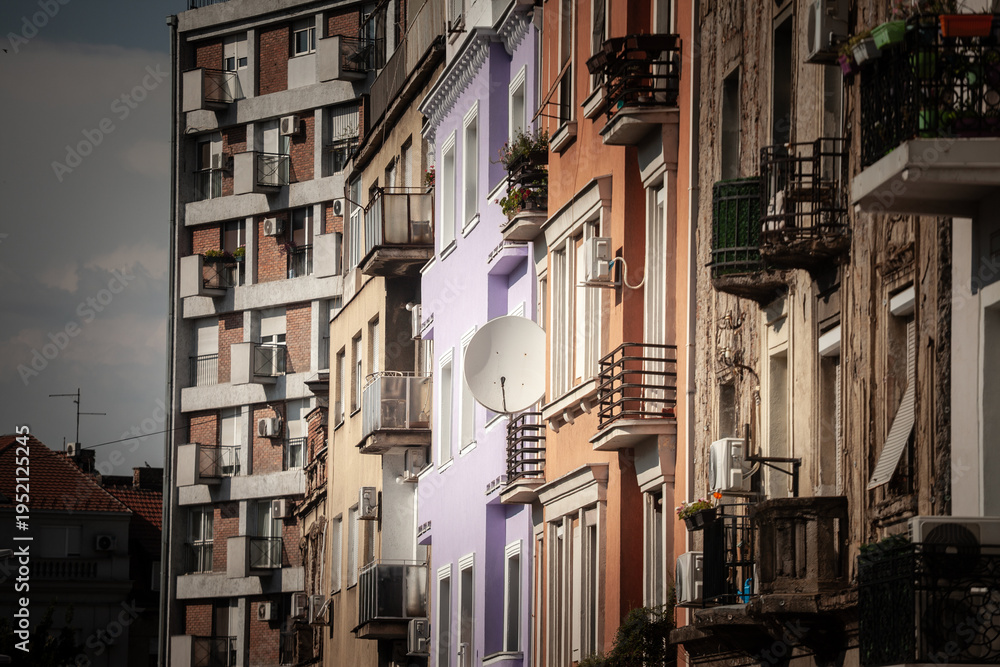 Fototapeta premium Satellite dish mounted on older residential buildings in Belgrade old town, Stari Grad, Serbia. The scene shows layered facades, balconies and urban housing details in a dense historic neighborhood.