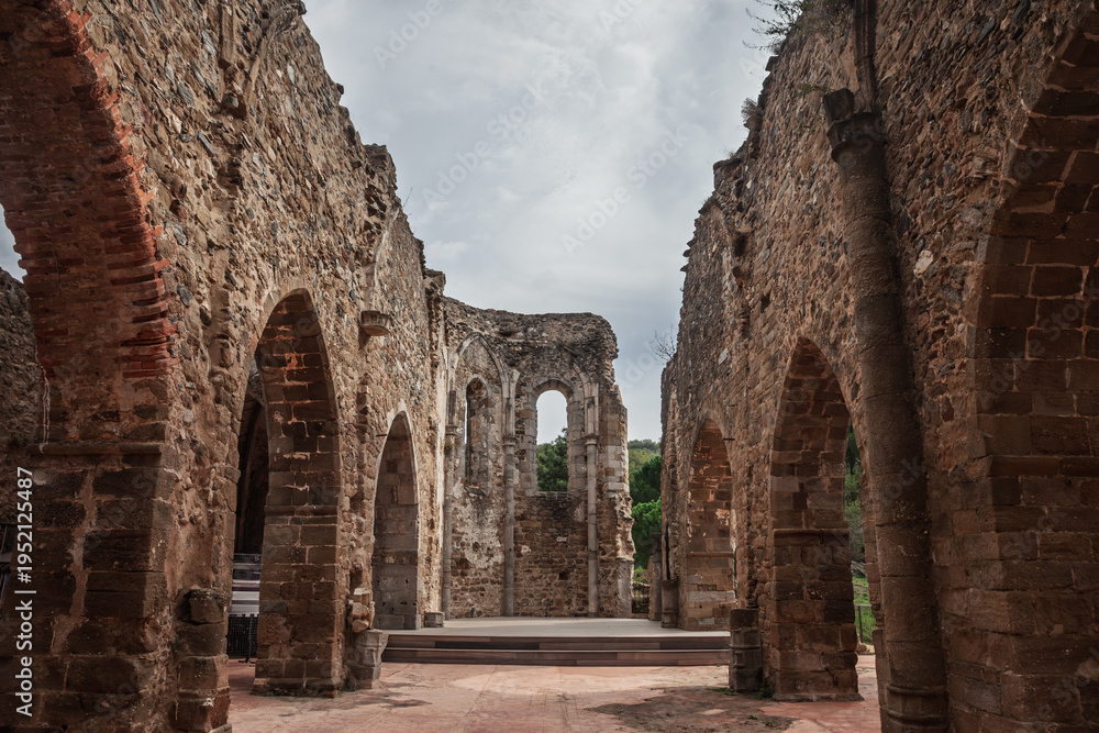 Fototapeta premium The ruins of the Old Saint-Pons Church, Ancienne Eglise Saint-Pons, in Collobrieres, France, showing stone arches, weathered walls and the open interior of the abandoned monument in Provence.